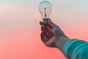A person holding a lightbulb depicting it lighting the way.