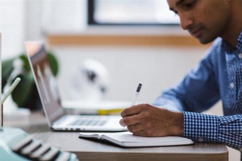 A researcher at a computer taking notes